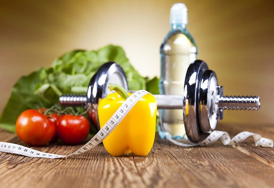 Mancuerna, verduras y cinta de centímetro